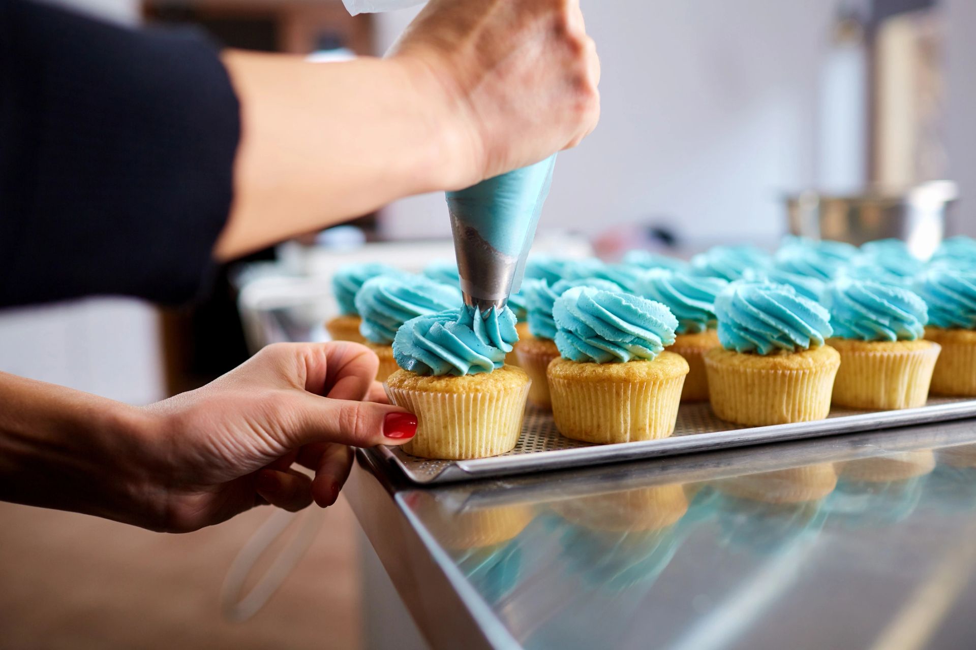 Cupcakes being frosted with swirls of icing